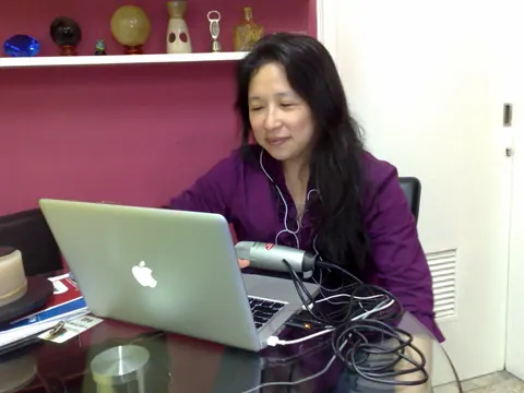 Janette Toral at a desk with a laptop and microphone, hosting an online session
